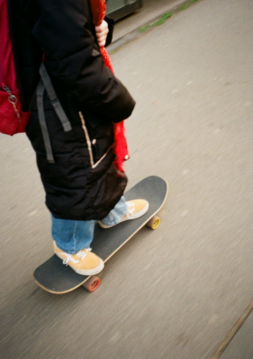 Person in yellow sneakers and blue jeans skateboarding on asphalt.
